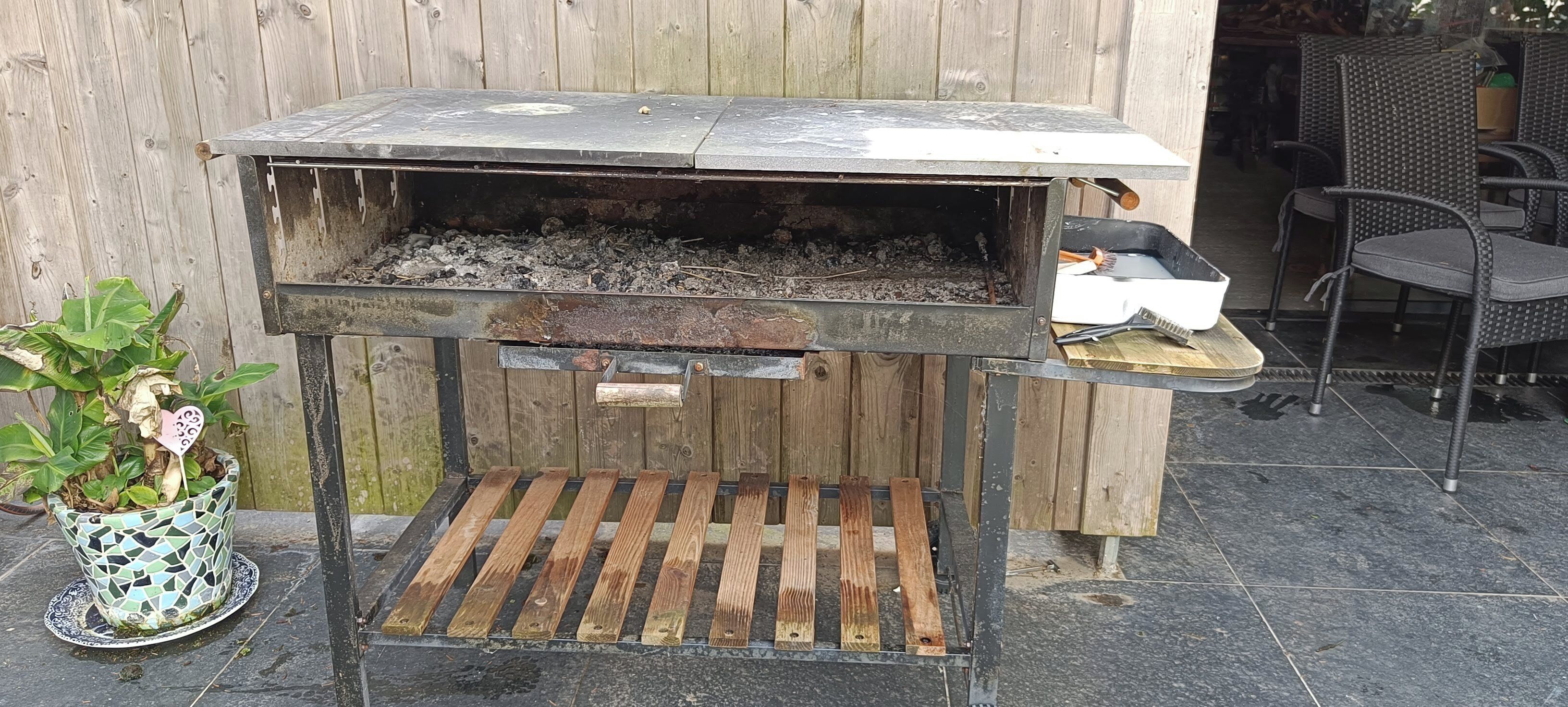 Una parrilla para barbacoa con una tapa de metal y un estante de madera.