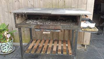 Una parrilla para barbacoa con una tapa de metal y un estante de madera.