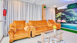 A living room with a sofa set, a glass coffee table, and a mural of a tropical scene. - iROOMZ Elite Casa Grand Inn (Hyderabad)