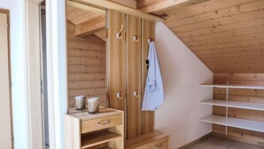 Une armoire en bois avec de nombreuses étagères et tiroirs, une tringle pour suspendre les vêtements et une serviette accrochée à la porte.
