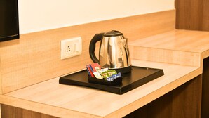 A kitchen counter with a kettle, a tray with tea bags, and a power outlet. - Hotel MM Continental (Varanasi)