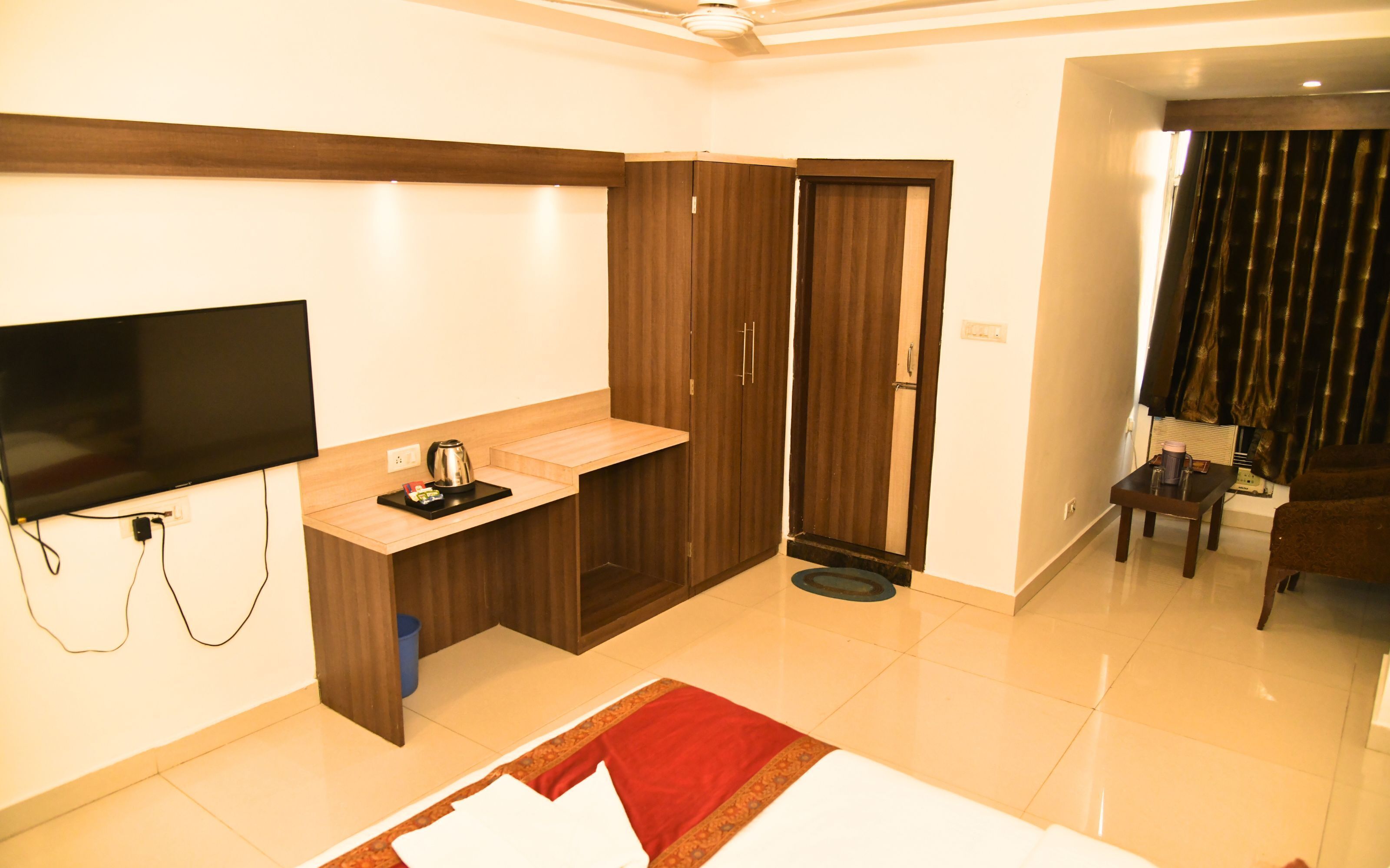 Habitación de hotel con televisión de pantalla plana, kitchenette pequeña, armario y cama.