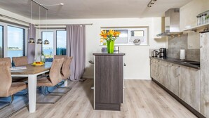 A modern kitchen with a central island, a dining area with a view, and a large window.