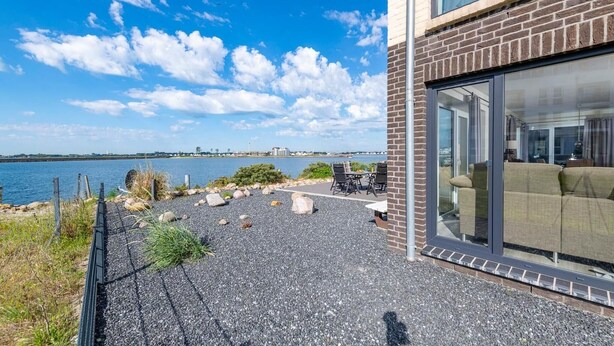 A modern building with a patio area featuring outdoor seating and a view of the water.