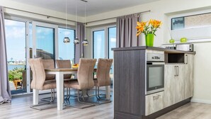 A modern kitchen with a built-in oven and a dining area with a table and chairs.