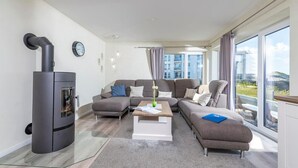 A modern living room with a built-in fireplace, a sofa set, a coffee table, and large windows offering a view of the city.