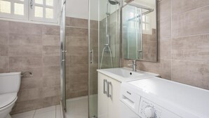 A modern bathroom with a glass shower enclosure, a toilet, and a sink with a mirror.