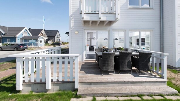 A two-story white building with a balcony and outdoor seating area. - Cozy home in Olpenitz with sauna (Olpenitz)