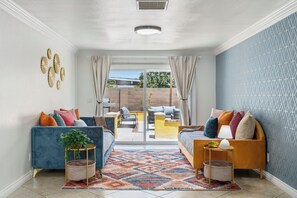 A living room with a blue sofa, a yellow sofa, and a coffee table. There is a patterned rug on the floor.