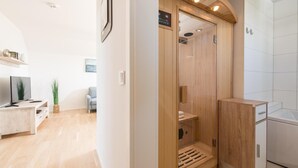 A modern bathroom with a wooden shower enclosure, a built-in toilet, and a separate sink area. - Nice apartment in Olpenitz with sauna (Olpenitz)