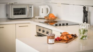 Une cuisine équipée d’un four à micro-ondes, d’une bouilloire et d’une planche à découper sur laquelle se trouvent des pâtisseries et des framboises.