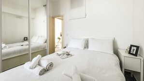 Une chambre d’hôtel avec un grand lit, une table de chevet sur laquelle se trouve un cadre photo et un miroir.