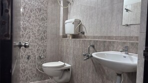 Une salle de bain équipée de toilettes, d’un lavabo et d’un porte-rouleau de papier toilette.
