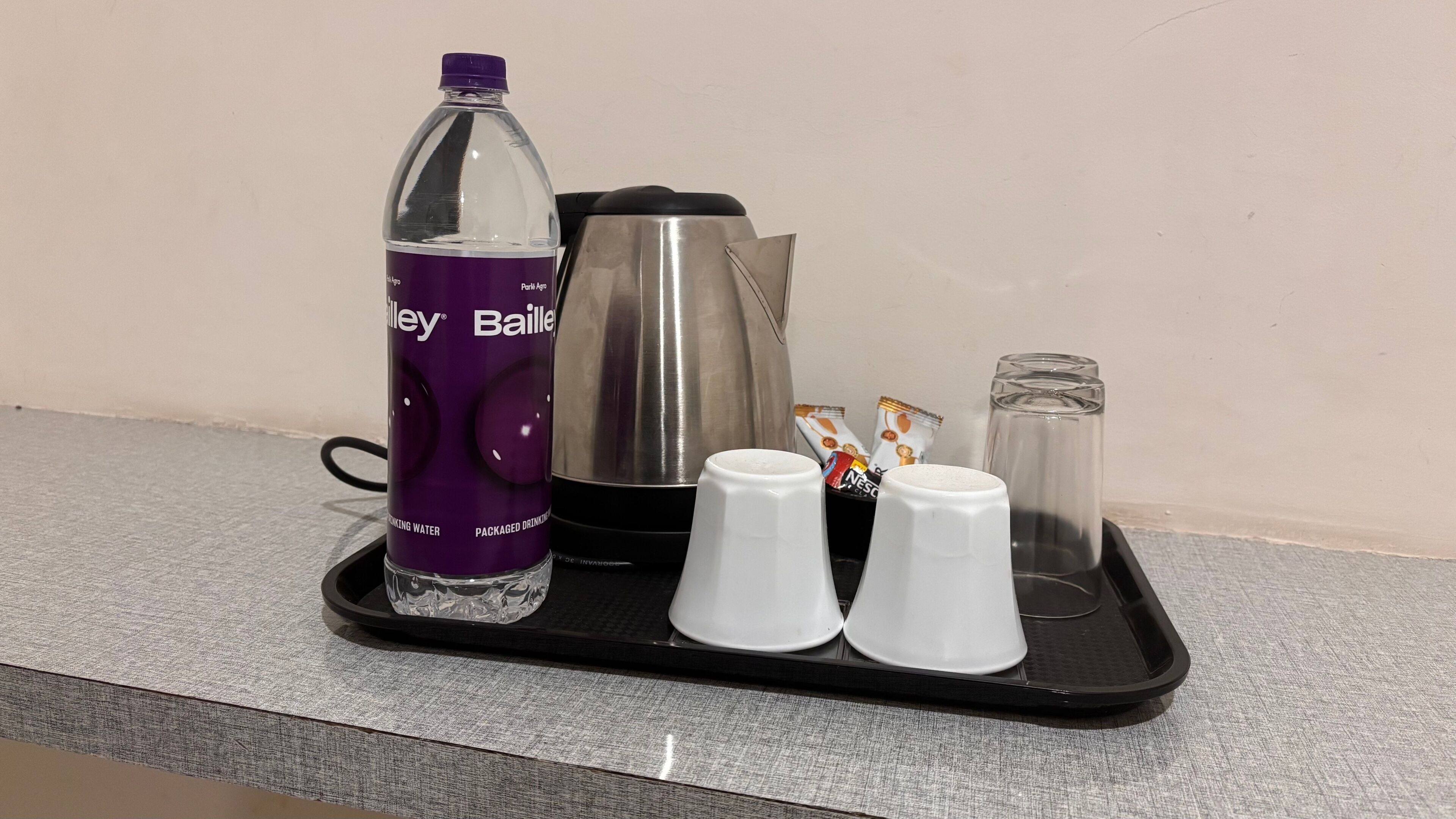 Ett bricka med en vattenflaska, en kaffebryggare, två koppar och en förpackning kaffe.