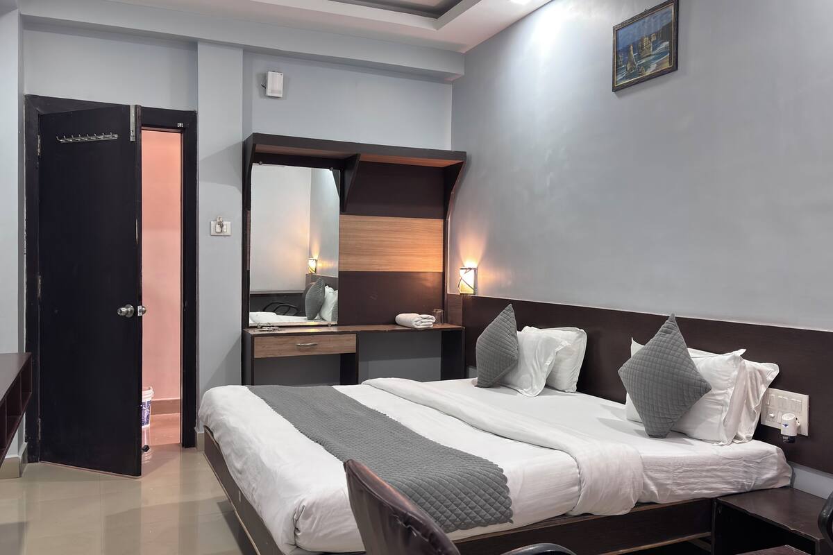 A hotel room with a bed, bedside table, mirror, and a wall-mounted picture.
