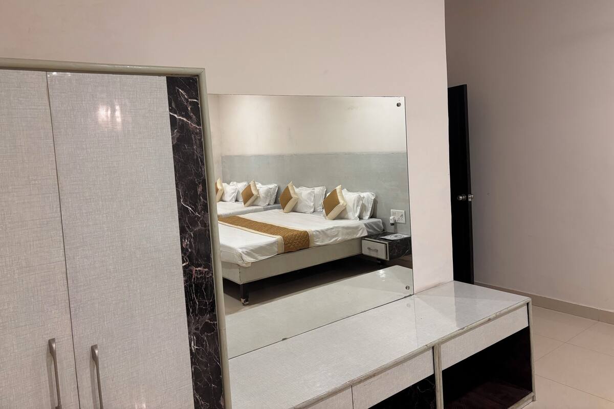 A modern hotel room with a large bed, a wardrobe, and a bedside table.