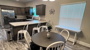 Une cuisine moderne avec un îlot central, des chaises blanches et une table à manger.