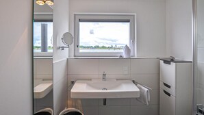 A modern bathroom with a window, a sink, a mirror, and a towel rack. - Beach front ship in Olpenitz with sauna (Olpenitz)