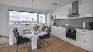 A modern kitchen with white cabinetry, a built-in oven, and a window overlooking a body of water. - Beach front ship in Olpenitz with sauna (Olpenitz)