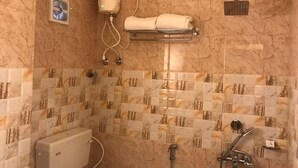 A bathroom with a toilet, a towel rack, a shower, and a water heater. - GHARANA RESORT (Chandannagar)