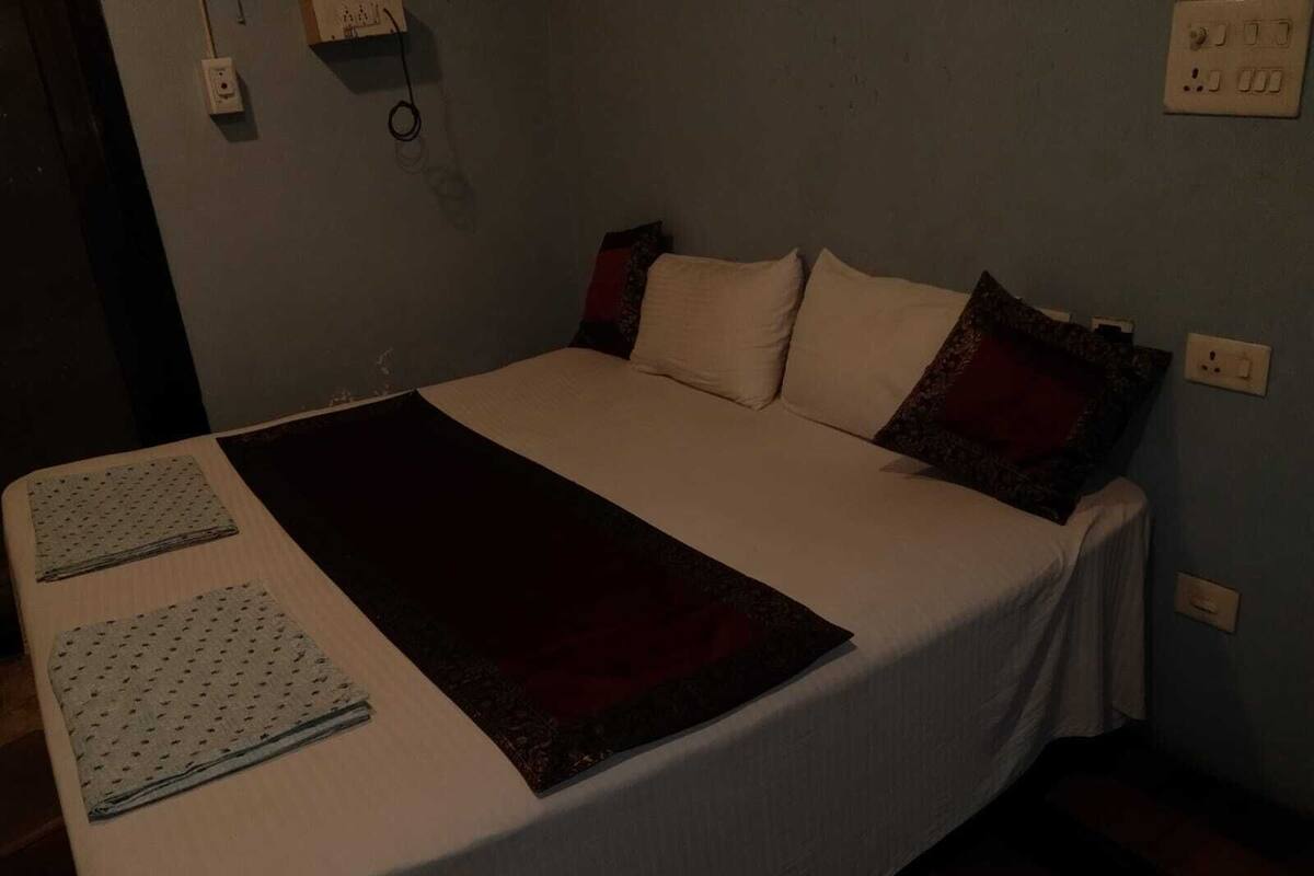 Una cama con una colcha blanca, dos almohadas y un edredón oscuro.