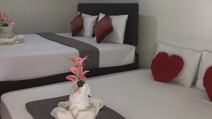Habitación de hotel con dos camas, un cuadro en la pared y un jarrón con flores sobre la primera cama.