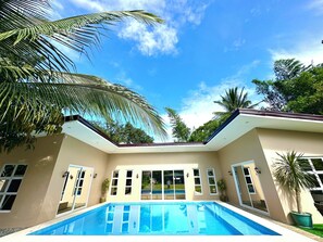 A modern house with a swimming pool, large windows, and palm trees. - Terra Vascileia Queen with Pool 32 Pax capacity (Amadeo)