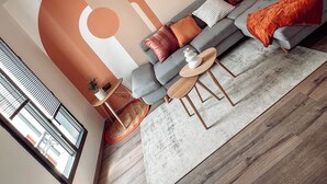 A modern living room with a grey sofa, wooden coffee table, and a large abstract wall mural. - NEW Duplex Hyper Centre Avec Piscine (Bergerac)