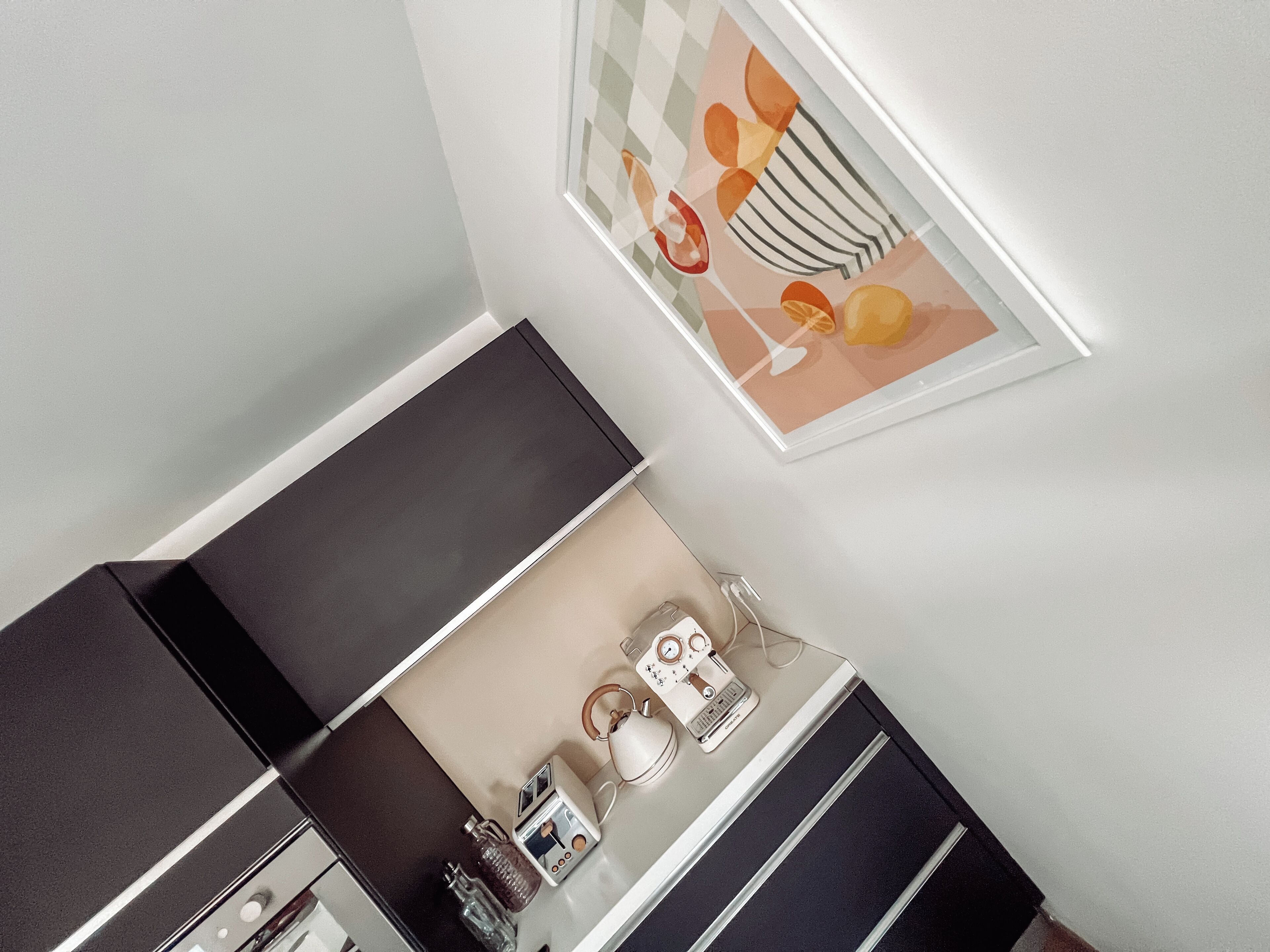A modern kitchen with a black countertop, a white appliance, and a framed picture on the wall.