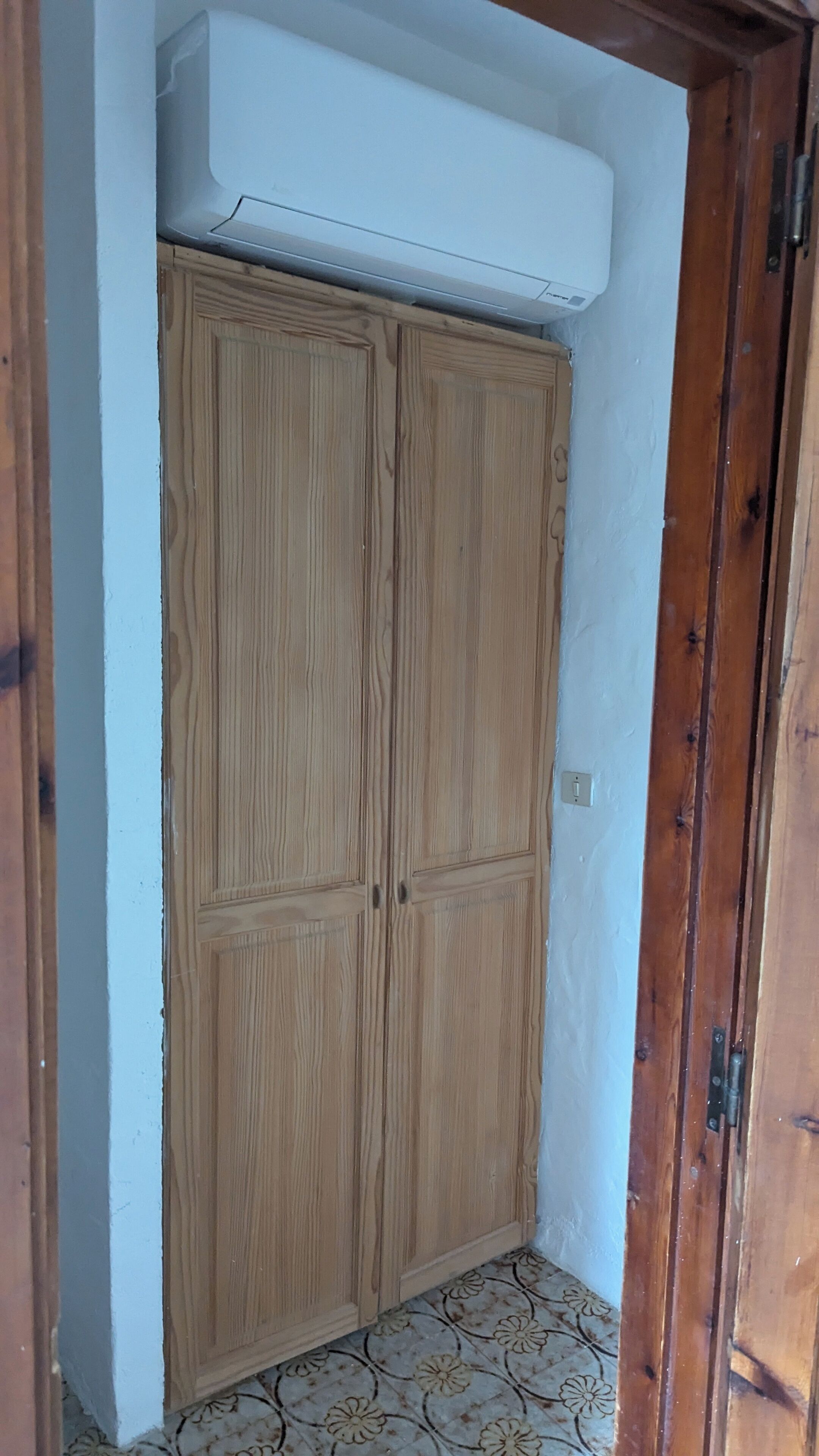 A wooden wardrobe with a built-in air conditioning unit above it.