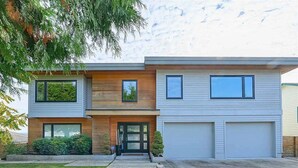 A modern two-story house with a garage, a front entrance, and a well-maintained lawn.