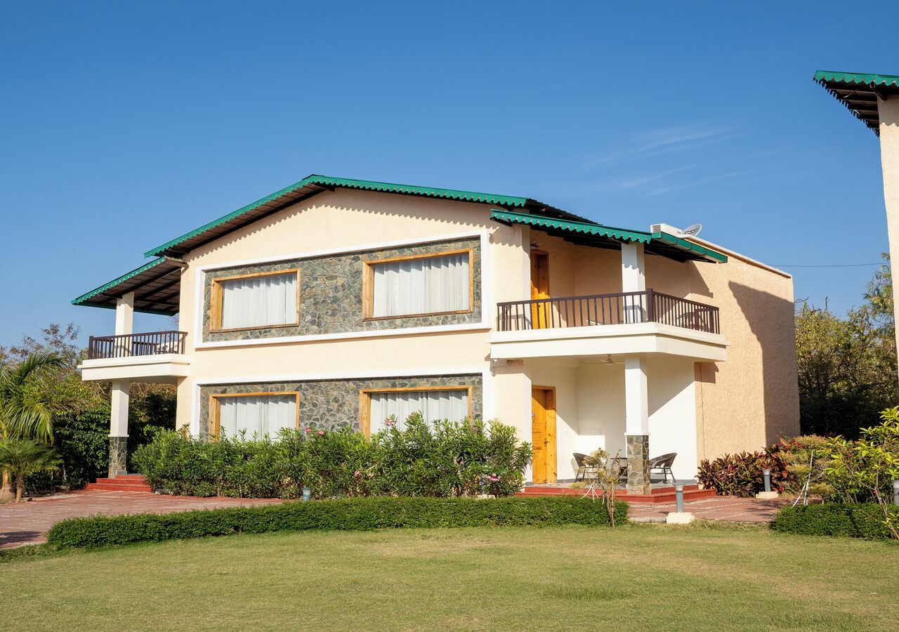A two-story house with a green roof, stone facade, and a balcony on the upper floor.