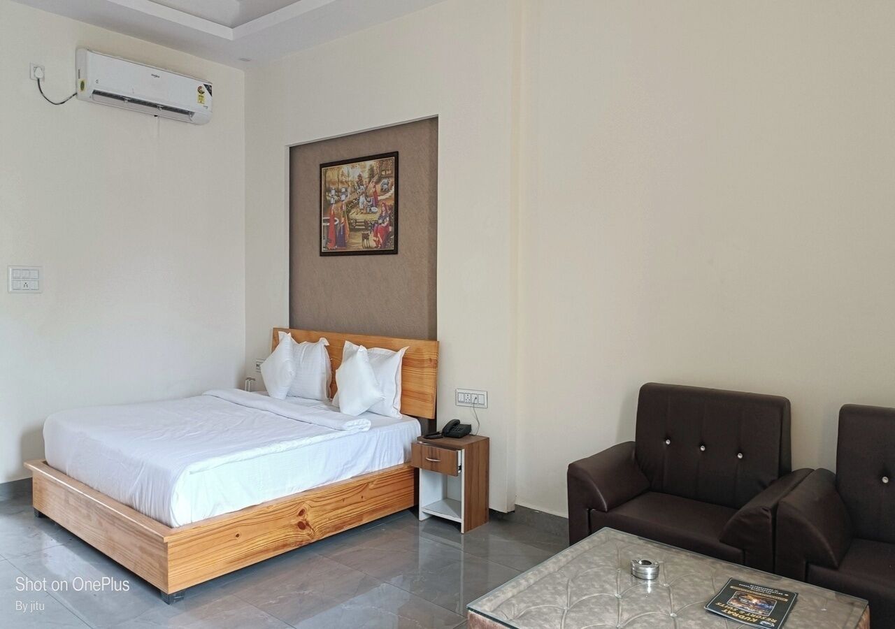 A hotel room with a wooden bed, a nightstand, a brown leather sofa, and a marble coffee table.