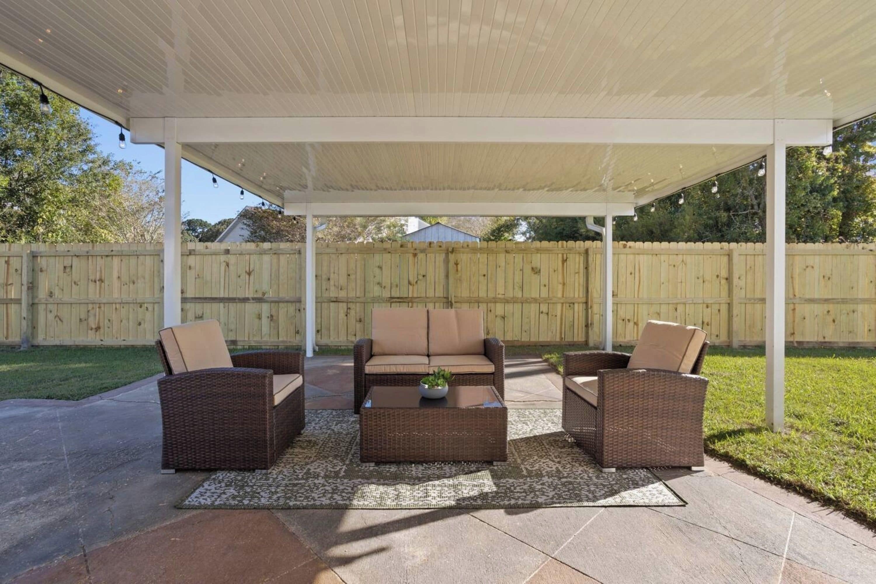 A covered patio area with wicker furniture, a coffee table, and a small plant.