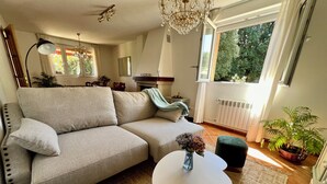 A living room with a sofa, a small table with a vase, a green ottoman, and a potted plant. - Casa Montañesa al Lado de la Playa (Somo)