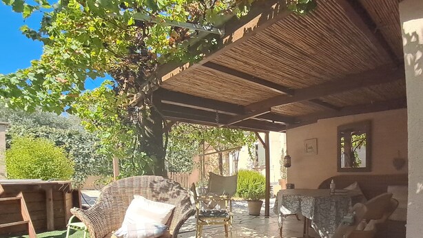 An outdoor patio with wicker furniture, a table, and a pergola providing shade. - Tramontane, bedroom, and TV room. Near Avignon. (Jonquerettes)