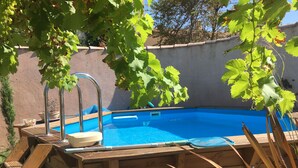 A wooden deck with a pool, surrounded by a wall and trees. - Tramontane, bedroom, and TV room. Near Avignon. (Jonquerettes)