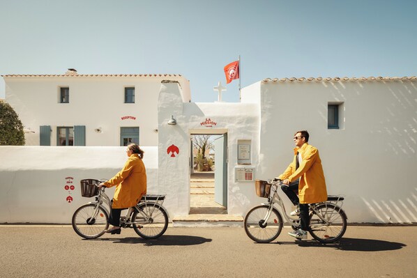 Deux personnes à vélo devant un bâtiment sur lequel on peut voir une enseigne indiquant « réception » et un drapeau.
