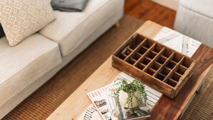 A wooden coffee table with a magazine, a small plant, and a wooden tray. - Benambra Cottage (Queenscliff)