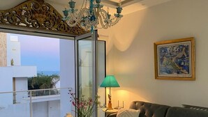 A living room with a glass coffee table, a sofa, a chandelier, and a painting on the wall. - Luxurious Sea View With Private Beach in Gammarth Marsa (La Marsa)