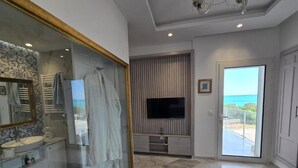 A bedroom with a bed, a TV, a bathroom with a mirror, and a balcony with a view. - Luxurious Sea View With Private Beach in Gammarth Marsa (La Marsa)