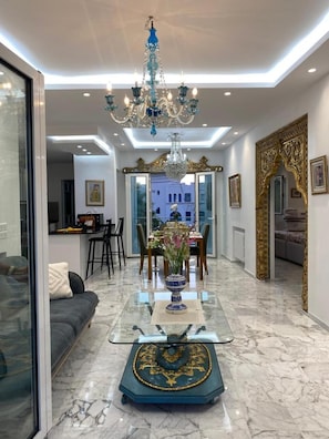 A modern interior with a glass coffee table, a chandelier, and a dining area. - Luxurious Sea View With Private Beach in Gammarth Marsa (La Marsa)