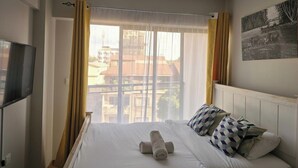 A hotel room with a bed, a TV, and a window with curtains. - Jali Stays, Serenity in Nairobi City (Nairobi)