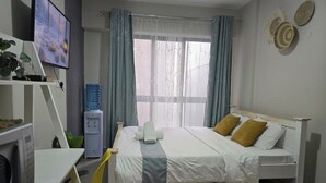 A bedroom with a bed, a TV, a water dispenser, and a desk with a chair. - Jali Stays, Serenity in Nairobi City (Nairobi)