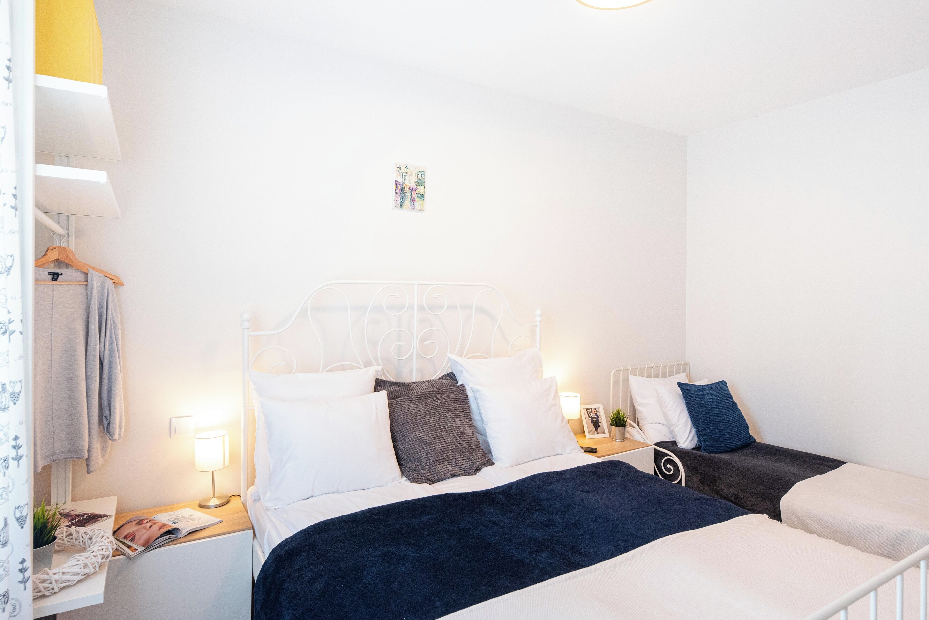 A bedroom with a bed, bedside tables, a lamp, and a small picture frame.
