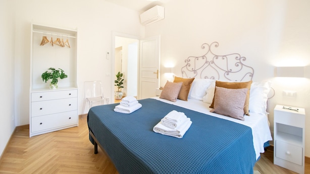 A bedroom with a bed, bedside tables, a wardrobe, and a mirror. - Singer House in Center Town (Lucca)