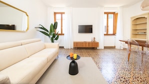 A living room with a sofa, a coffee table with two cups, a TV, and a plant. - Singer House in Center Town (Lucca)