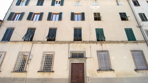 A multi-story building with a beige facade, multiple windows with shutters, and a central door. - Singer House in Center Town (Lucca)