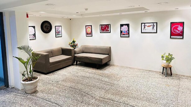 A modern waiting area with two sofas, a potted plant, and a wall decorated with framed artwork. - Qotel Comfort Golden Saffron Punjabi Bagh (New Delhi)