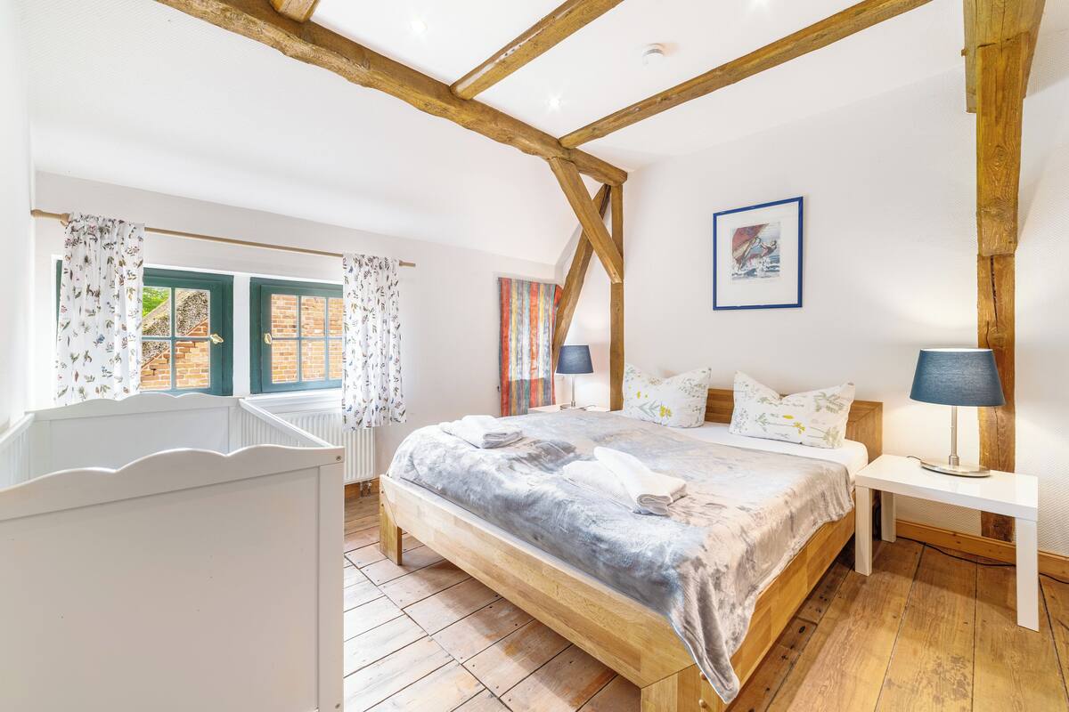 A bedroom with a wooden bed, white nightstands, and a window with curtains.